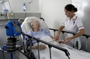 Old lady in bed overlooked by nurse Old lady in bed overlooked by nurse
